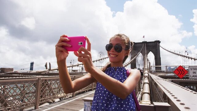 New York. Happy selfie tourist woman taking picture with phone app on Brooklyn Brige, New York City, Manhattan, USA. Video of real unretouched woman model without any makeup
