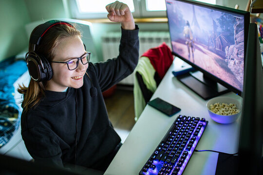 Teen girl gamer celebrating victory at home desk
