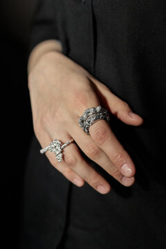 Vertical shot of young adult womans hand displaying statement rings against dark background, highlighting luxury fashion styling and jewelry detail. Ideal for accessory branding and retail marketing