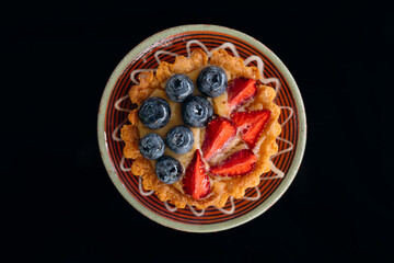 Gourmet berry tartlet on plate isolated on black background, flat lay. © sav_an_dreas