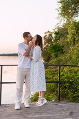 Fototapeta premium Romantic couple sharing a tender kiss on a wooden pier at sunset