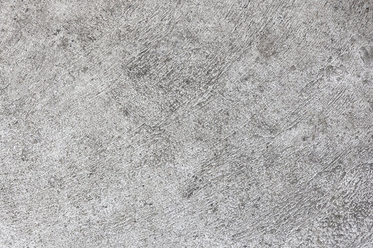 Rough gray concrete texture with visible trowel marks, pores and scratches. An industrial wall background ideal for architecture, construction, graphic design and product mockups