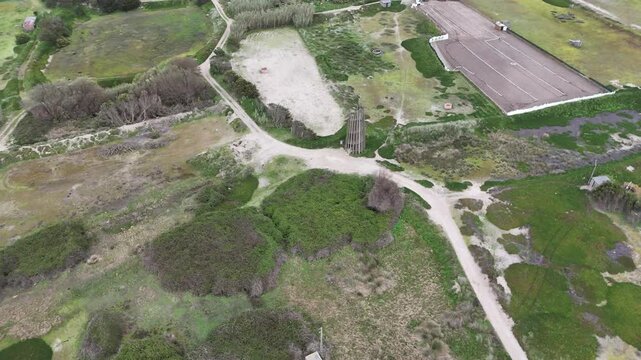 Aerial view of a lush rural landscape in Belinho, Portugal. Drone performs a boom down, tracking shot, and pan right, revealing winding paths and a observation tower.