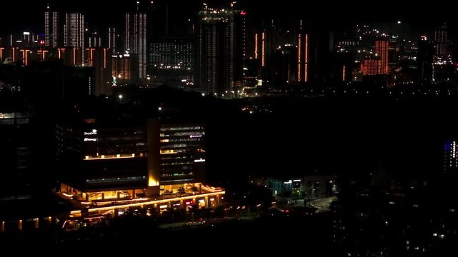 illuminated Accenture building with road, vehicles and skyscrapers at khajaguda, nanakramguda, hyderabad, telangana, india. night time, trucking shot, drone shot, 4k.