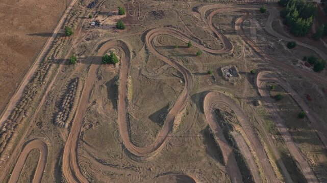 Aerial drone footage of the Central Otago Motorcycle Club motocross track in Cromwell, New Zealand, featuring winding dirt circuits, jumps, berms, and off-road riding terrain.