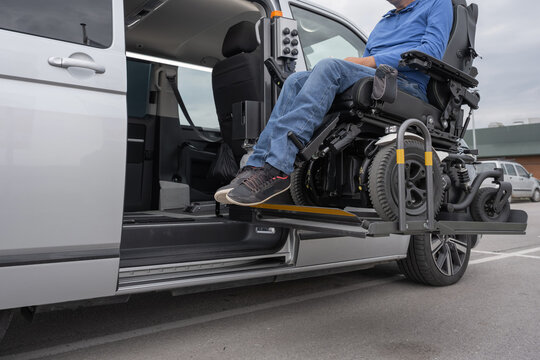 Powered wheelchair user boarding an adapted van with a lift platform for independent mobility and travel. Accessible transportation concept.