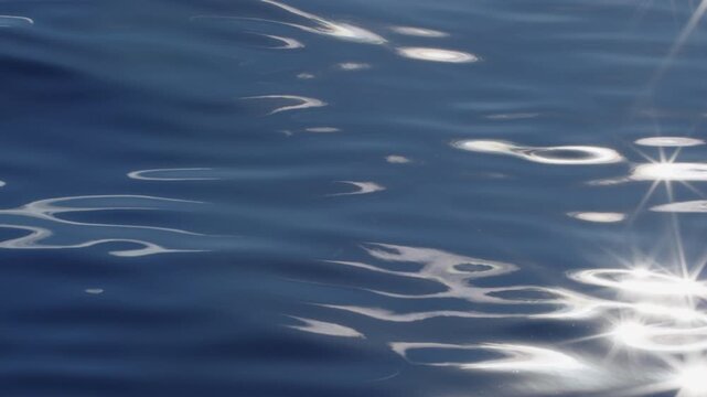 Sea surface with blinking stars and flares as seen from the moving sailing boat