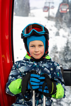 Portrait of cute confident pensive little kid boy enjoy having fun sit ski lift gondola at alpine mountain skiing resort on bright winter day. Toddler beginner skier rest of training in ski school