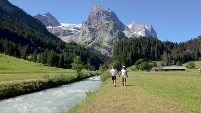Switzerland is a paradise for nature lovers, featuring stunning mountain views and serene river paths. A diverse couple of men and woman on vacation in the Swiss Alsp