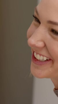 Vertical video: Smiling woman lifting gaze, laughing in warm room, wearing red-and-white headband