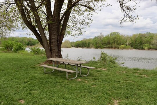 The empty picnic table near the river in the park.