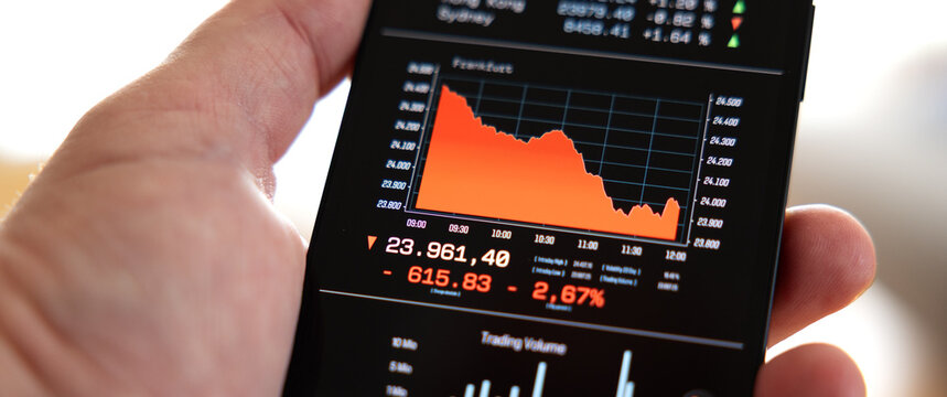 Hand holds a smart phone, market data and a falling German stock market chart on screen, recession, crash. Risk, volatility, wireless technology, online broker, financial market, invest.
