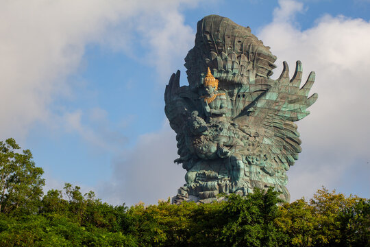 Colossal Garuda Wisnu Kencana statue of Vishnu on the Garuda rising above green treetops, GWK Park, Ungasan, Bali, Indonesia.