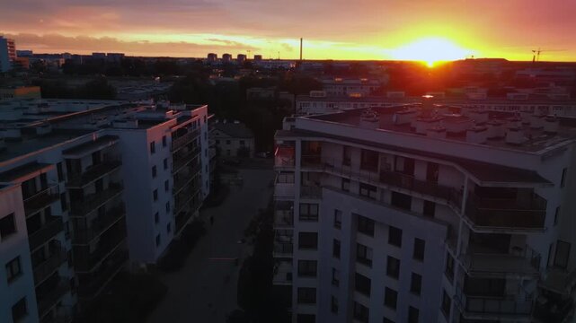 Aerial view of a medium-sized city with numerous densely populated housing estates during sunset.