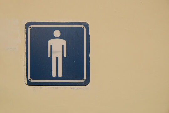 Close up of a male toilet symbol information icon on a painted wall with copy space. Public restroom signage with clean graphic design. Suitable for navigation, accessibility, hygiene, and facility 