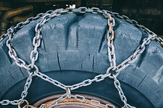 Heavy duty tire with metal snow chains, ready for winter conditions and challenging terrain, ensuring strong grip and mobility