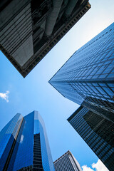 Naklejka premium Downtown Manhattan skyscrapers. Low angle view of modern glass financial district towers rising into blue sky in NYC.