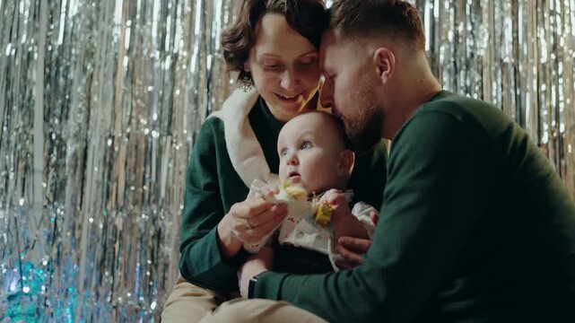 A joyful family of three celebrating New Year together at home, surrounded by festive decorations. The parents, dressed in cozy outfits, cherish moments with their baby. Celebrating New Year