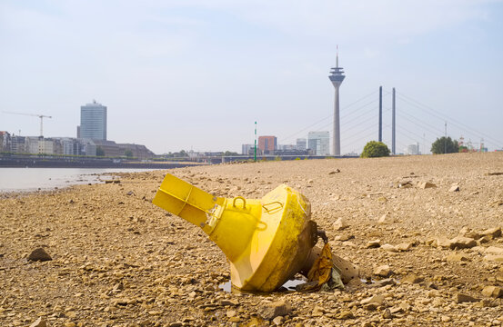 Low stream gauge of rhine river.Water shortage, drought, climate change,global warming concept, dry river bed with skyline of the town of d&uuml;sseldorf, germany in the background