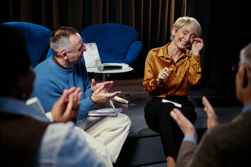 Obraz na płótnie Canvas Middle aged business group applauding smiling Caucasian woman speaking during panel discussion, showing recognition and teamwork. Ideal for leadership, corporate event, communication use