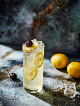 tom collins cocktail  with lemon peel and cherry garnish