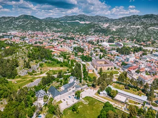 Cetinje historic city, Montenegro, featuring its famous monastery, National Museum, and surrounding mountains under a blue sky © EdNurg