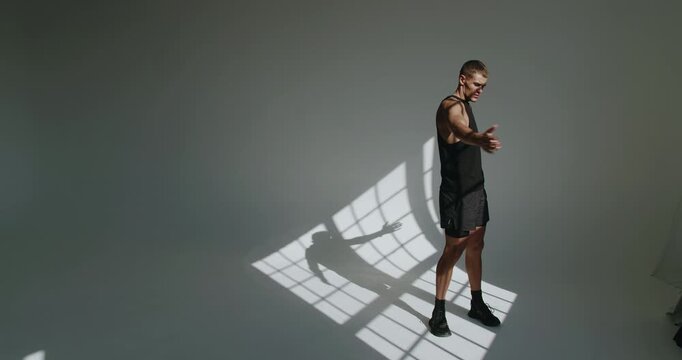 Man with an athletic build performs physical training indoors. His focused expression and powerful stance emphasize strength and endurance. Athletic Young Man Training in a Modern Studio Environment