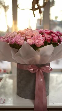 Luxurious arrangement of roses in an elegant hat box with satin ribbon. Romantic floral gift concept.