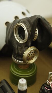 A classic Soviet-era black rubber gas mask (GP-5) with a green filter attached stands on display.
