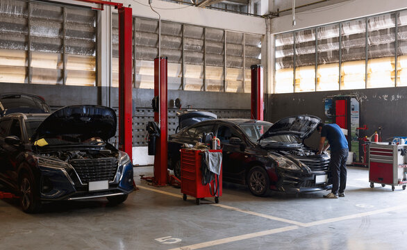Car Repair Service Garage with Mechanic Inspecting Engine