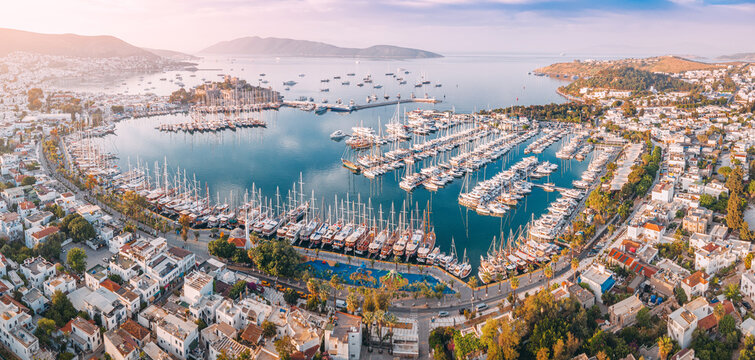 Aerial view of Bodrum harbor, many sailboats and yacht docks, and coastal city views at sunset in Turkiye