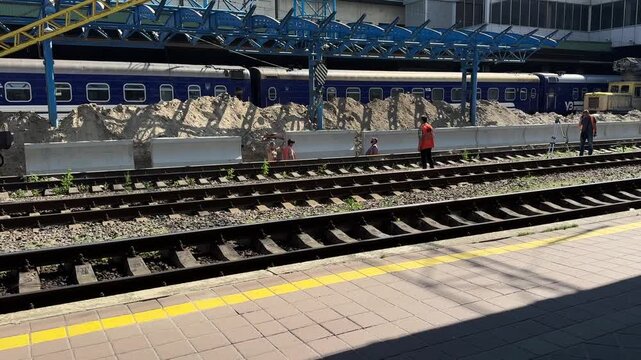 Railway Station Track Maintenance With Construction Workers Repairing Rail Infrastructure Beside Passenger Train Platform Area