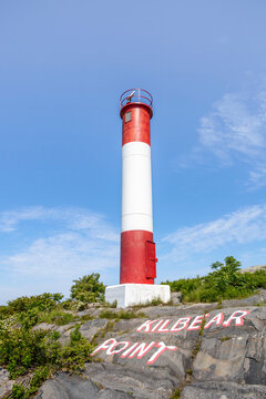 Red and white lighthouse atop rugged terrain in Killbear Provincial Park, Ontario.