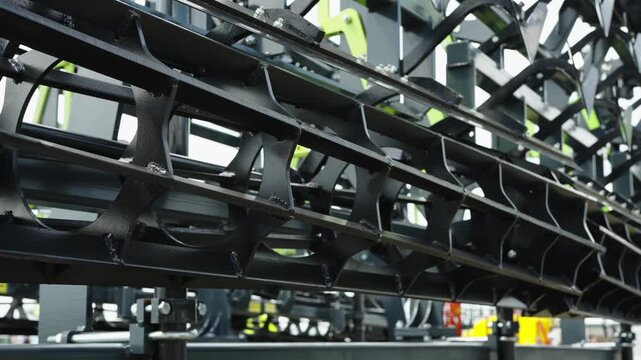 A close-up shot focuses on the black cage rollers and cultivation tines of a modern agricultural soil tillage implement.