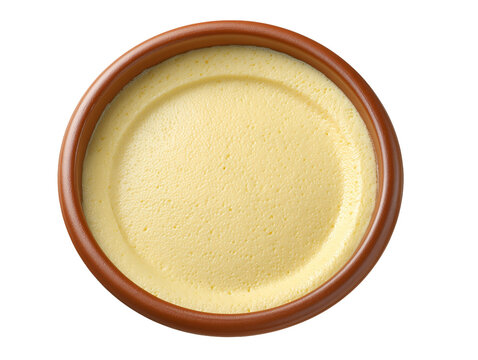 Top view of smooth and creamy vanilla pudding in a ceramic ramekin, isolated on a white background.
