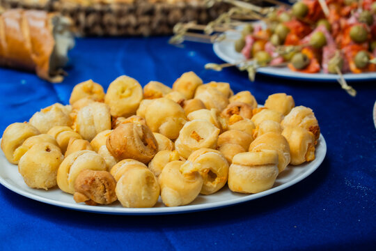 Plato de pasabocas de hojaldre horneados con relleno salado sobre mesa de catering para eventos