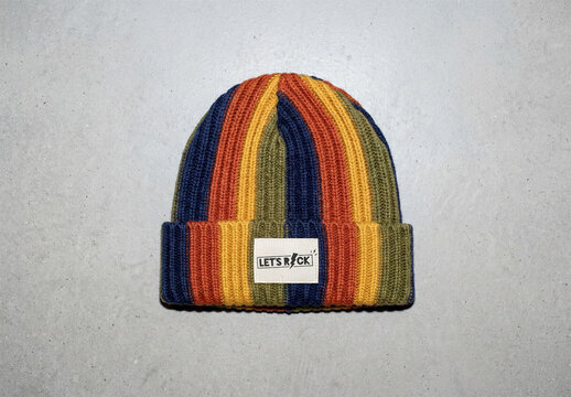A wool beanie with white label and with a colorful striped pattern lies flat on a light surface. 