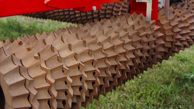 A close-up shot shows the heavy, cast-iron ring sections of a Cambridge roller or cultipacker used for soil compaction.