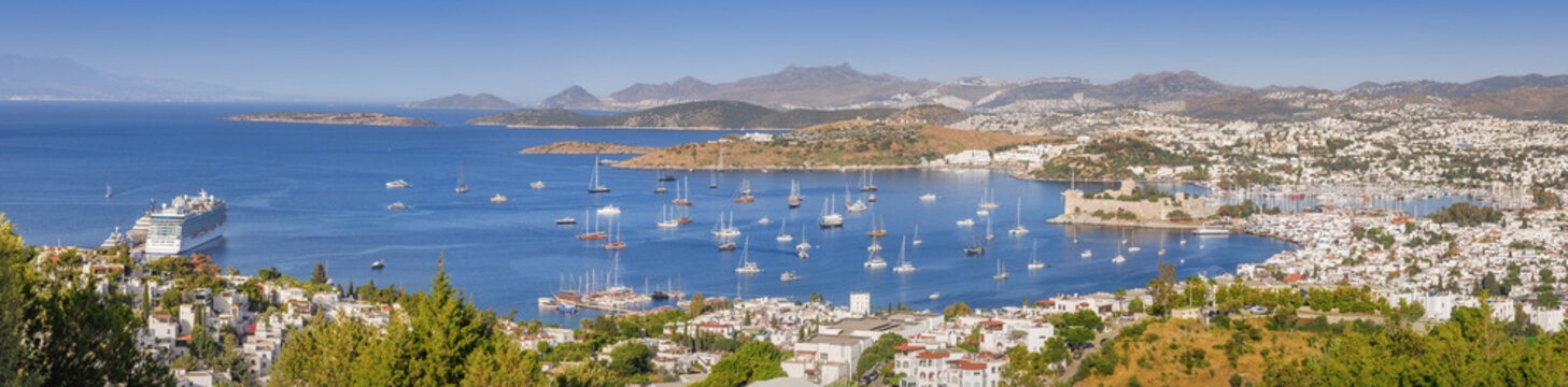 Bodrum cityscape with white houses and a historic castle overlooking the Aegean Sea, full of yachts and a large cruise ship
