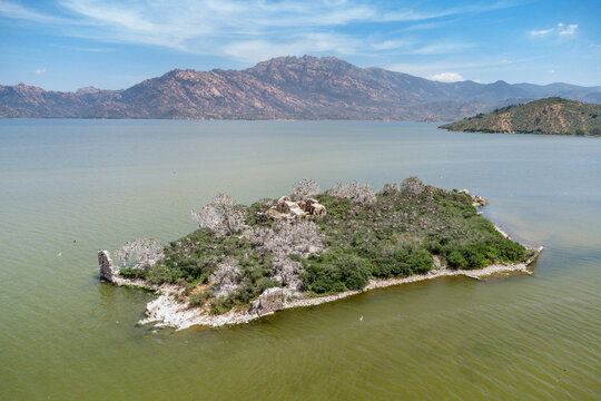 island showing ancient monastery ruins and arid trees surrounded by Bafa Lake with Latmos Mountains in background