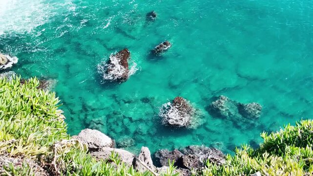 Aerial panning view reveals turquoise sea water and submerged rocks along the antalya cliffside.