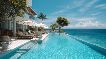 Fototapeta premium Serene Luxury Poolside Oasis with Ocean View Under a Clear Sky and Lush Greenery in a Tropical Setting