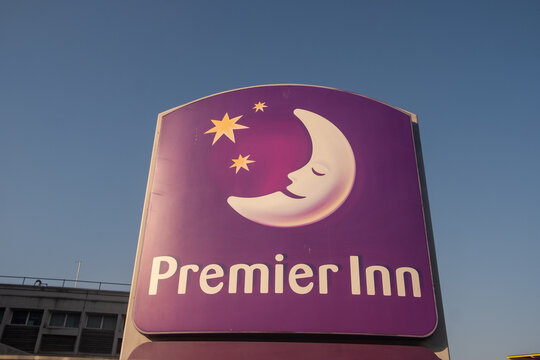 LONDON - Premier Inn Sign, Putney Bridge &ndash; Purple hotel logo with crescent moon against clear blue sky.