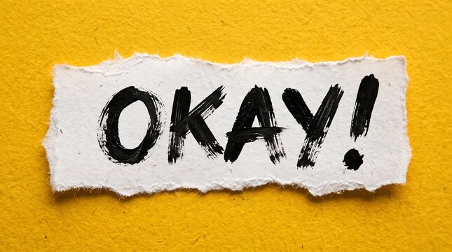 Handwritten "OKAY!" in black ink on a torn white paper strip, set against a bold, vibrant yellow background, perfect for confirmation, agreement, and expressive design projects.