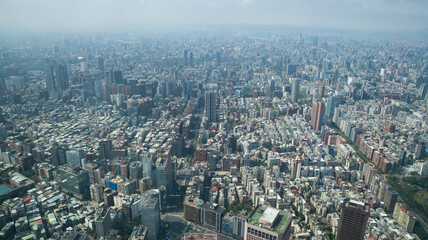 Obraz premium Expansive aerial view of Taipei city skyline from Taipei 101 observatory showing densely packed urban buildings stretching to the hazy horizon across the Taiwanese capital.