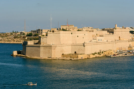Vista panor&aacute;mica del Fuerte San &Aacute;ngel en Vittoriosa, Malta, un basti&oacute;n hist&oacute;rico de piedra caliza, con una embarcaci&oacute;n tradicional cruzando el Gran Puerto.