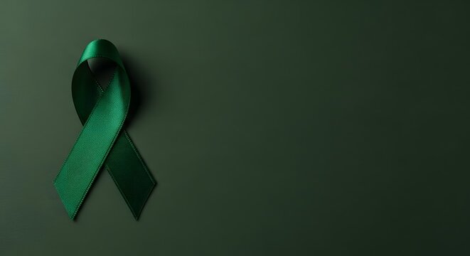 Green awareness ribbon on dark background. Symbol for mental health support. Medical charity sign.
