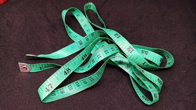 Flexible yellow tailor measuring tape with black millimeter and inch markings coiled neatly lying on a clean surface macro close up studio shot with soft bright lighting for sewing tailoring fashion d