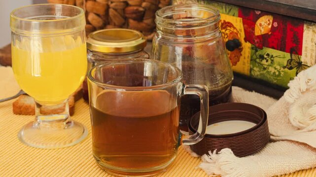 Healthy breakfast spread showing a jar of natural honey, a mug of hot tea, a glass of fresh orange juice, ripe peaches and an apple, and toasted rusks for a wholesome and nutritious meal.