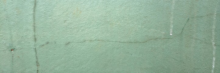 Green concrete wall showing weathered texture with cracks and urban decay © Harry